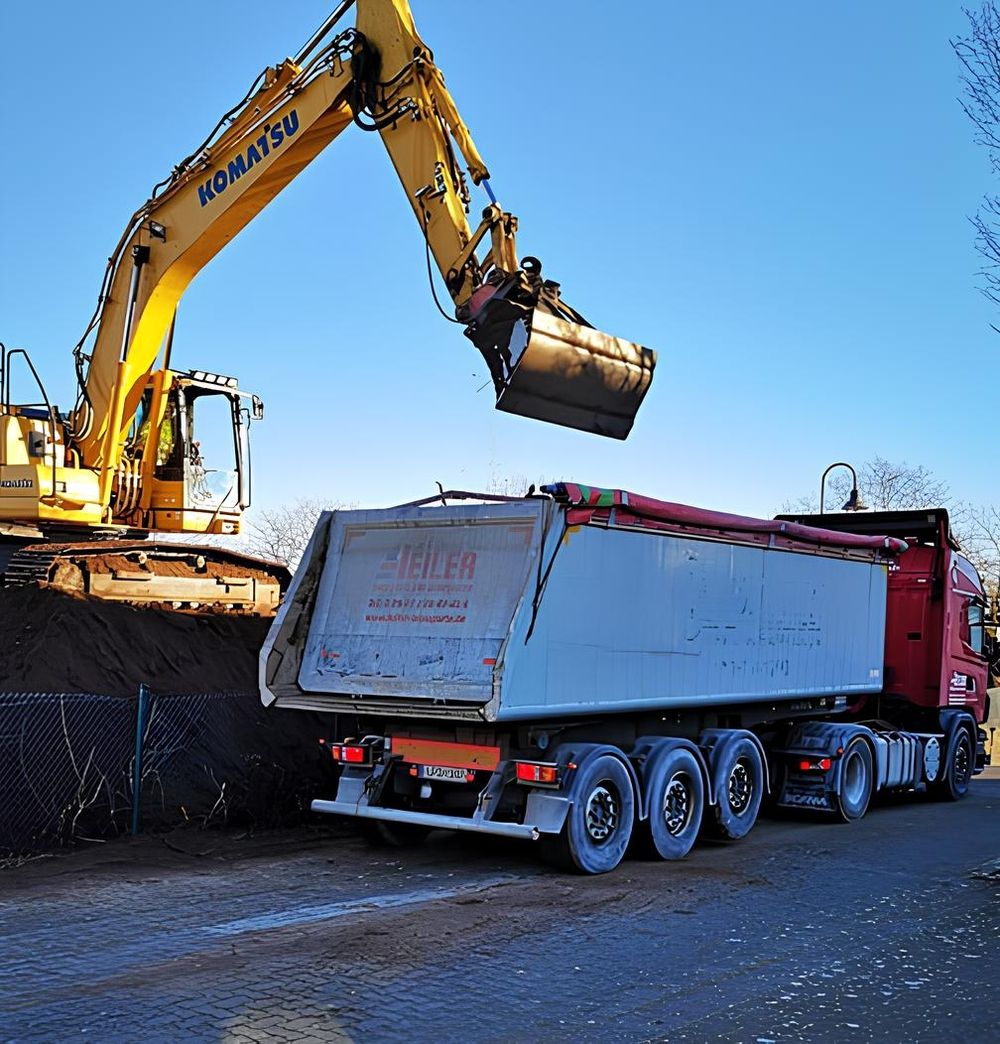 Bagger entlädt Schotter vom LKW