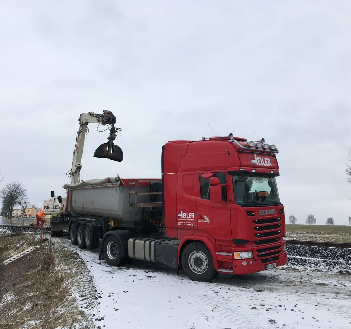 ein Bagger und ein LKW auf der Straße bei Schnee